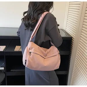 Detail of pink fabric crossbody bag with multi-zipper pockets and wide shoulder strap