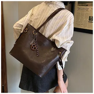 Detail view of large dark brown tote bag with vintage lychee grain leather and bag charm