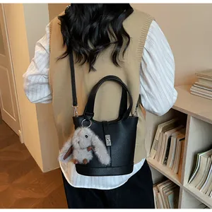 Detail of black pebbled leather bucket bag with silver buckle and grey rabbit charm