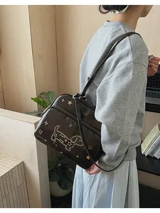 Détail d'un sac à main en cuir verni avec broderie de teckel et étoiles colorées