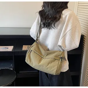 Detail of the olive green nylon crossbody bag showing the dual zipper pockets and strap