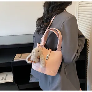 Pink lychee grain leather bucket bag with metal buckle and plush rabbit charm detail