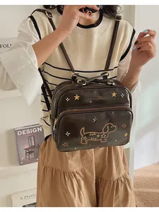 Détail de la broderie teckel et étoiles colorées sur sac en similicuir marron foncé