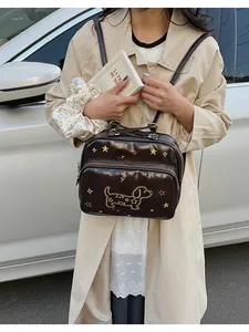 Détail du sac à main en cuir marron avec broderie d'étoile dorée et motif teckel
