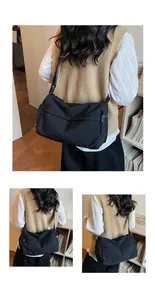 Detail view of the black crossbody bag with wide strap and multiple zipper pockets