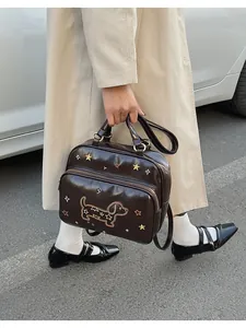 Détail d'un sac en cuir marron brillant avec broderie de teckel et petites étoiles