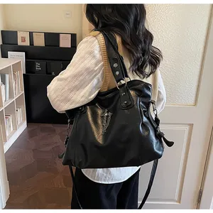 Dettaglio della borsa tote in pelle nera retrò con croce in metallo argento e ciondolo