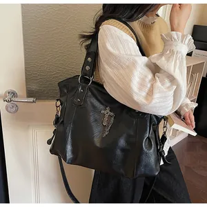 Dettaglio della borsa tote in pelle PU nera con pendente a croce argento e catene metalliche