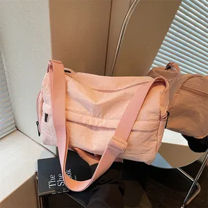 Pink minimalist nylon crossbody bag with adjustable wide strap shown in a modern interior setting