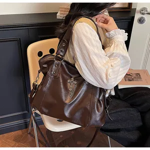 Dettaglio della borsa tote in ecopelle marrone con ciondolo a croce argento e catena
