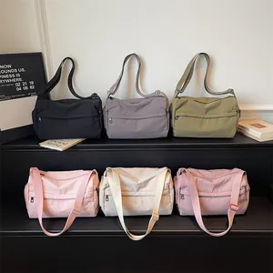 Fashionable nylon crossbody bags in multiple colors displayed on a black step stand