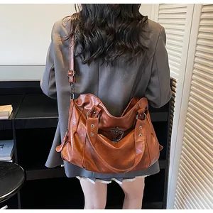 Dettaglio di una borsa tote marrone vintage con texture retrò e ciondolo a croce