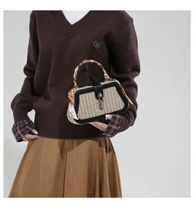 Detail van geweven handtas met leren bies, gouden ringsluiting en decoratieve sjaal