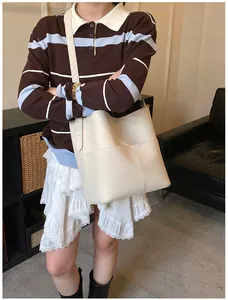 Modell mit cremeweißer Beuteltasche aus Leder mit Kieselstein-Narbe und langen Trägern