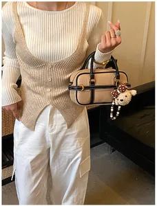 Dettaglio della borsa in pelle beige con finiture a contrasto e ciondolo a forma di orso