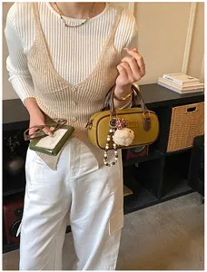 Detail of vintage mustard yellow bowling bag with plush charm and model holding green wallet
