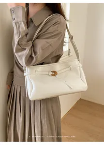 Minimalist white shoulder bag with vintage gold buckle detail shown on model
