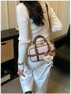 Dettaglio mini borsa boston in pelle martellata con ciondolo a orsetto e tracolla marrone