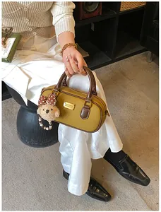 Detailed view of yellow bowling bag with brown handles and cute bear charm accessory