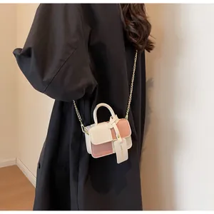 Detail view of the elegant beige and pink contrast handbag with a golden chain strap