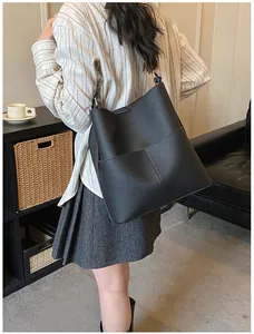Detailansicht einer schwarzen Beuteltasche mit Kreuznaht und Lederstruktur am Modell