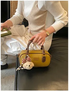 Detail of yellow bowling handbag with a plush puppy charm and vintage PU leather texture