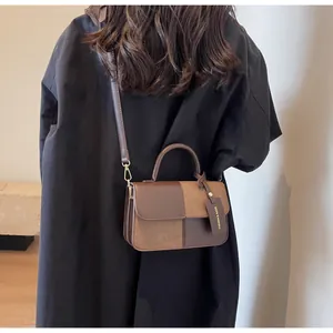 Detail of color-block leather crossbody bag with metal magnetic clasp and fashion tag