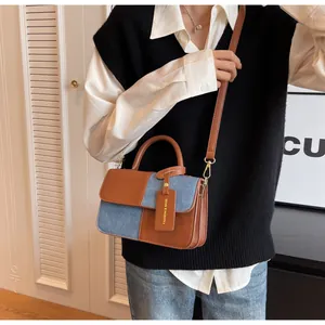 Detail view of fashion square bag with brown leather and blue denim patchwork design