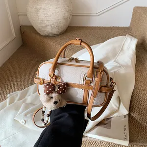 Borsa Boston vintage color crema con bordi marroni e ciondolo a orsetto in posa lifestyle