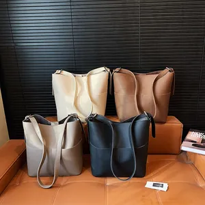 Minimalistische Leder-Beuteltaschen in vier Farben mit breiten Schultergurten auf Sofa