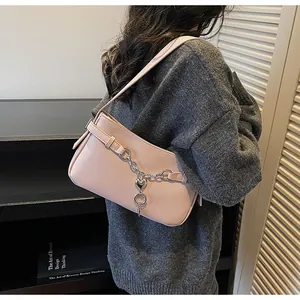 Détail du sac à bandoulière rose en simili cuir avec chaîne argentée et breloque cœur