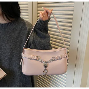 Détail du sac porté épaule en cuir grainé rose avec chaîne à cœur argenté et pendentif