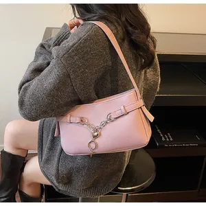 Détail du sac baguette en cuir rose avec chaîne cœur argentée et décor d'anneau métallique