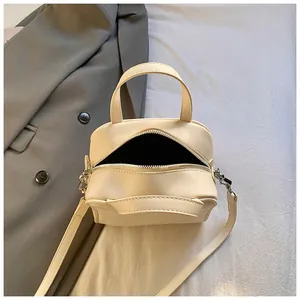 Close-up of beige bowling style handbag with top zipper and soft faux leather texture