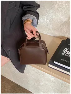 Detail of dark brown minimalist leather handbag with smooth texture and sturdy top handles