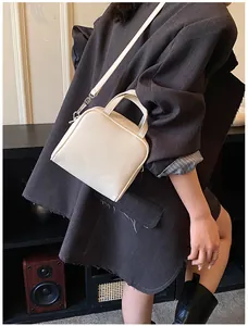 Model wearing a minimalist cream PU leather crossbody bag with a grey oversized blazer