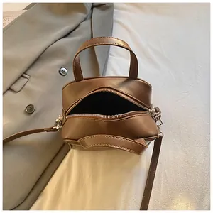Minimalist dark brown leather crossbody bag with top handle and silver zipper closure