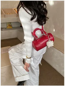 Detail of red cylinder Boston bag with cute white plush sheep charm on white outfit