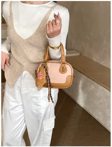 Detailed view of pink and brown leather crossbody bag with cute plush monkey pendant