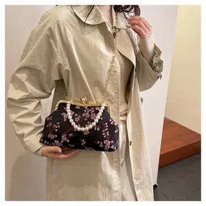 Detail der Vintage-Blumentasche mit Perlengriff und goldener Kette am Modell