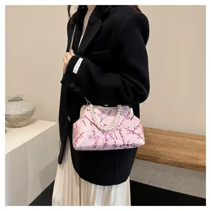Detail of pink satin handbag with floral embroidery, pearl handle and gold chain