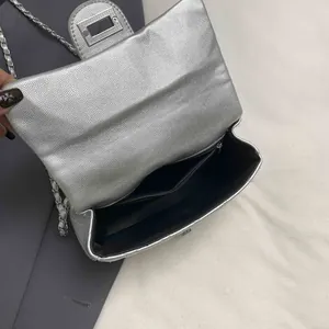 Silver quilted chain bag with lychee texture and open interior compartment showing lining