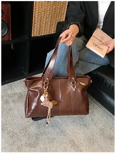 Detail einer braunen Vintage-Tote-Bag aus glänzendem Öl-Leder mit süßem Pferdeanhänger