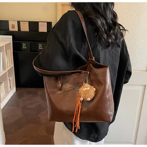 Détail d'un sac cabas marron chaud avec pendentif en peluche et logo pour le bureau