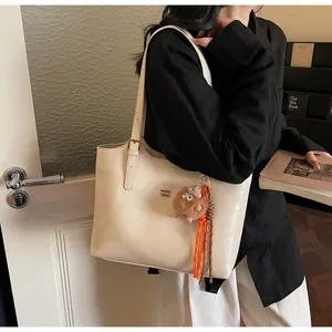 Sac fourre-tout crème chic avec logo en métal, charme en peluche et bandoulières
