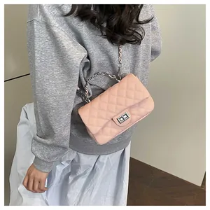 Detail view of pink quilted chain shoulder bag with metal handle and twist lock closure