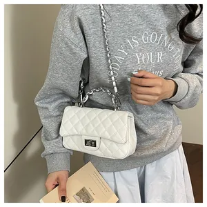 Close-up of quilted white leather crossbody bag with silver chain and twist lock detail