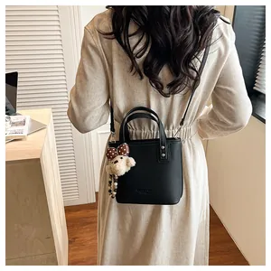 Close-up of black litchi grain leather bucket bag with cute plush bear charm detail