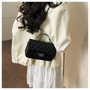 Detail of black quilted leather shoulder bag featuring silver chain strap and metal clasp