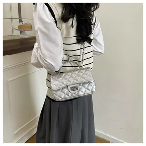Detail view of silver quilted crossbody bag with metallic chain strap and turn-lock closure